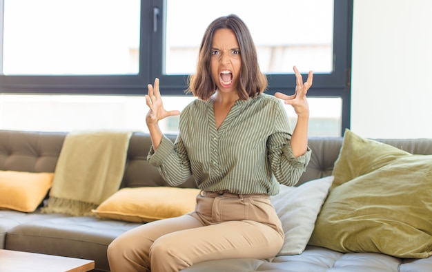 Mujer bonita joven relajándose en casa en un sofá