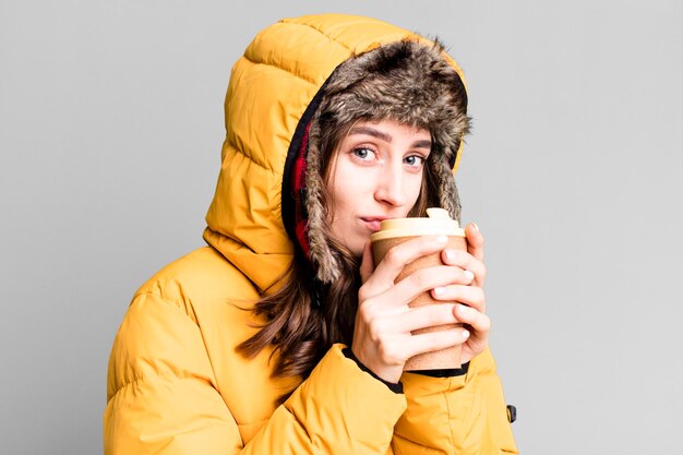 Foto mujer bonita joven con ropa de invierno y un concepto de frío e invierno de café caliente