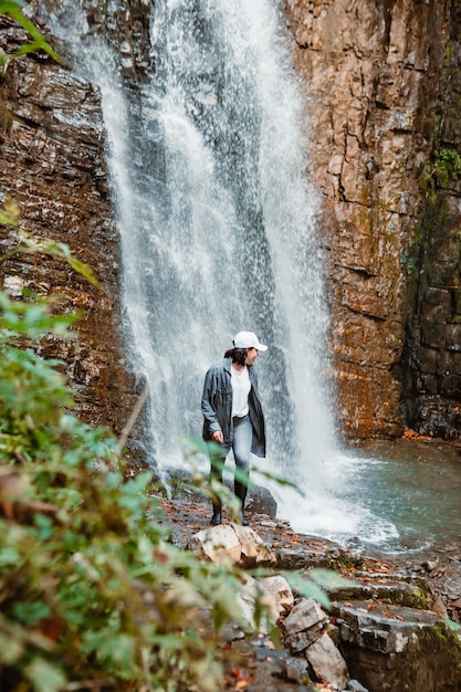 Mujer bonita joven senderismo disfrutando de la vista del espacio de copia de cascada