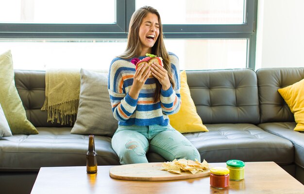 Mujer bonita joven sentada en un sofá de cuero comiendo