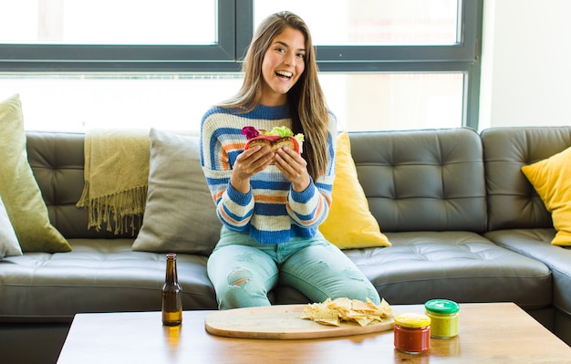 Mujer bonita joven sentada en un sofá de cuero comiendo