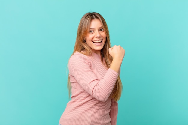 Mujer bonita joven sintiéndose feliz y enfrentando un desafío o celebrando