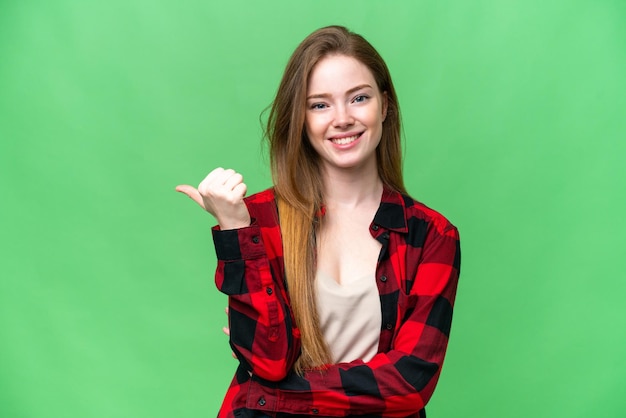 Mujer bonita joven sobre fondo clave de croma aislado apuntando hacia un lado para presentar un producto