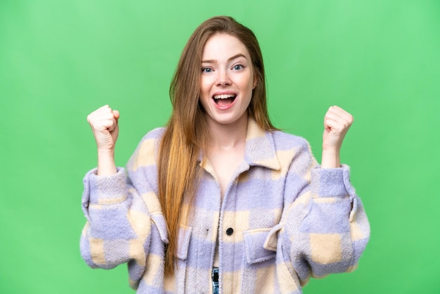 Mujer bonita joven sobre fondo clave de croma aislado celebrando una victoria en posición de ganador