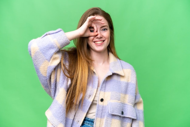 Mujer bonita joven sobre fondo clave de croma aislado que muestra el signo ok con los dedos