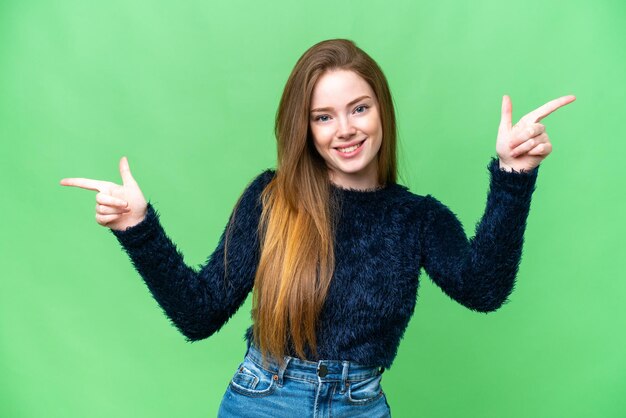 Mujer bonita joven sobre fondo clave de croma aislado señalando con el dedo a los laterales y feliz