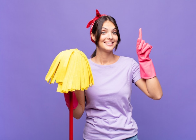 Mujer bonita joven sonriendo alegre y felizmente, apuntando hacia arriba con una mano para copiar el espacio