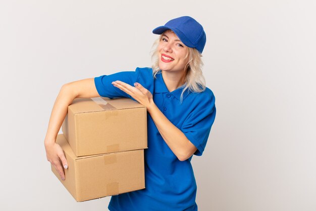 Mujer bonita joven sonriendo alegremente, sintiéndose feliz y mostrando un concepto. concepto de entrega de paquetes