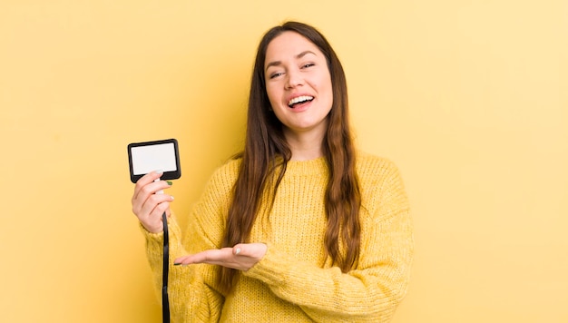 Mujer bonita joven sonriendo alegremente sintiéndose feliz y mostrando un concepto de pase vip concepto