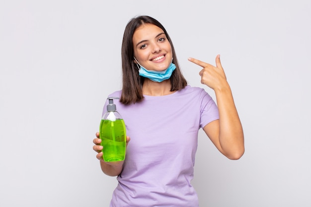 Mujer bonita joven sonriendo con confianza apuntando a su propia sonrisa amplia, actitud positiva, relajada y satisfecha