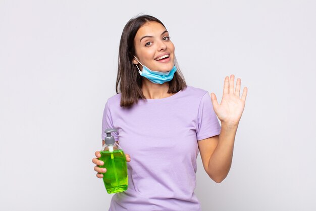 Mujer bonita joven sonriendo feliz y alegremente, saludando con la mano, dándote la bienvenida y saludándote, o diciéndote adiós