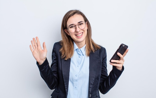 Mujer bonita joven sonriendo felizmente agitando la mano dándole la bienvenida y saludando su concepto de negocio