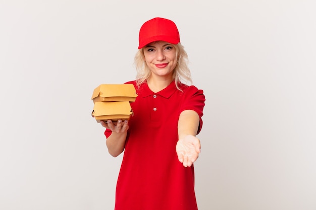 Mujer bonita joven sonriendo felizmente con amable y ofreciendo y mostrando un concepto. concepto de entrega de hamburguesas