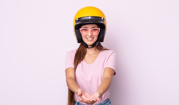 mujer bonita joven sonriendo felizmente con amable y ofreciendo y mostrando un concepto. motociclista y casco