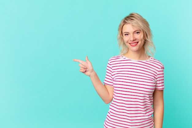 Mujer bonita joven sonriendo felizmente con una mano en la cadera y confiada. concepto de espacio de copia