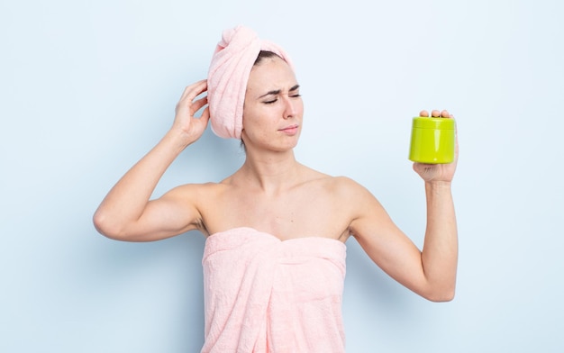 Mujer bonita joven sonriendo felizmente y soñando despierto o dudando. concepto de producto de ducha y cabello