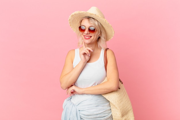 Mujer bonita joven sonriendo felizmente y soñando despierto o dudando. concepto de turismo de verano