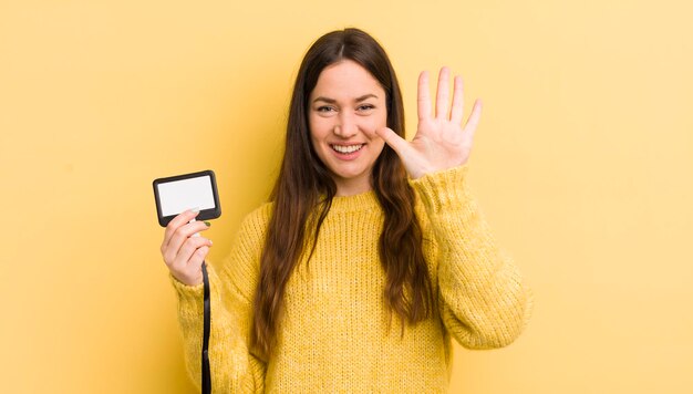 Mujer bonita joven sonriendo y luciendo amigable mostrando el concepto de pase vip número cinco