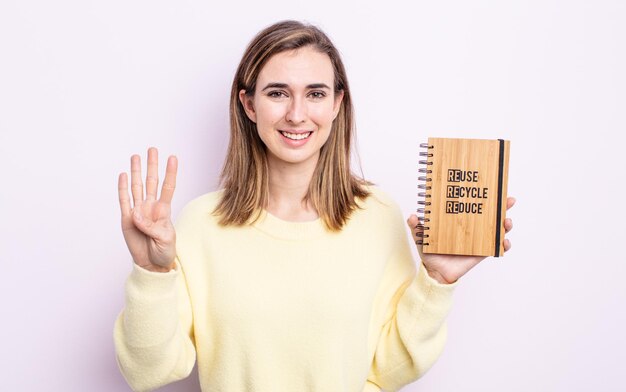 Mujer bonita joven sonriendo y luciendo amigable, mostrando el número cuatro. concepto de reciclaje