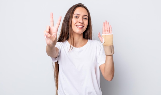 mujer bonita joven sonriendo y luciendo feliz, gesticulando victoria o paz. concepto de vendaje de mano