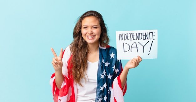 Mujer bonita joven sonriendo y mirando amigable, mostrando el concepto número dos del día de la independencia