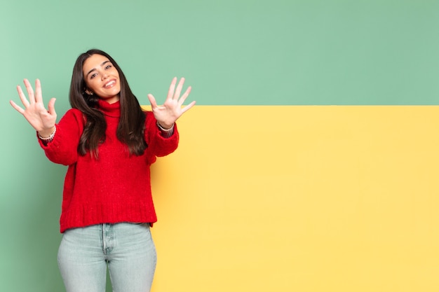 Mujer bonita joven sonriendo y mirando amigable, mostrando el número diez o décimo con la mano hacia adelante, contando hacia atrás. copia espacio para colocar tu concepto