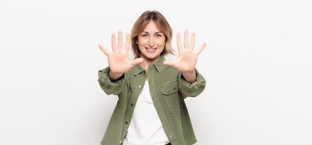 Mujer bonita joven sonriendo y mirando amistosamente, mostrando el número diez o décimo con la mano hacia adelante, contando hacia atrás