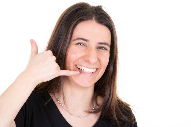 Mujer bonita joven sonriendo mostrando gesto llámame teléfono con los dedos aislado sobre fondo blanco.