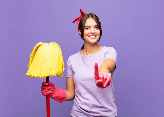 Mujer bonita joven sonriendo con orgullo y confianza haciendo el número uno