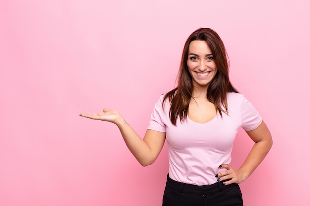 Mujer bonita joven sonriendo, sintiéndose confiada, exitosa y feliz, mostrando algo