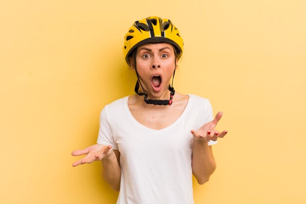 Mujer bonita joven sorprendida sorprendida y asombrada con un increíble concepto de bicicleta sorpresa