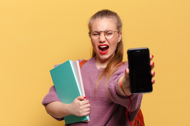 Mujer bonita joven sosteniendo carpetas y smartphone