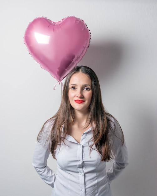 Mujer bonita joven sosteniendo un globo de aire en forma de corazón