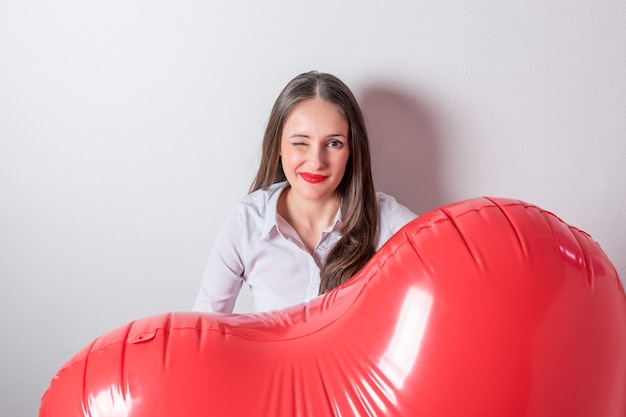 Mujer bonita joven sosteniendo un globo de aire en forma de corazón