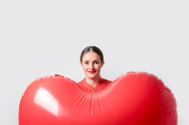 Mujer bonita joven sosteniendo un globo de aire en forma de corazón