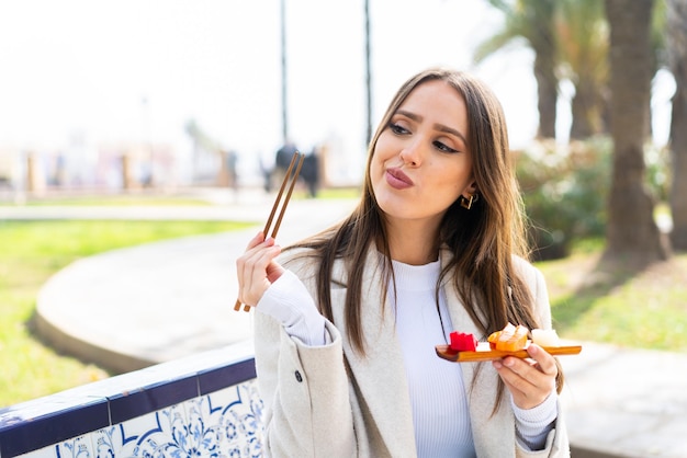 Mujer bonita joven sosteniendo sashimi al aire libre