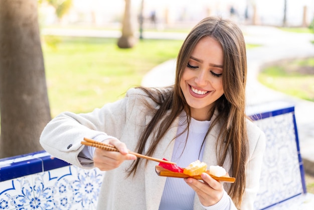 Mujer bonita joven sosteniendo sashimi al aire libre