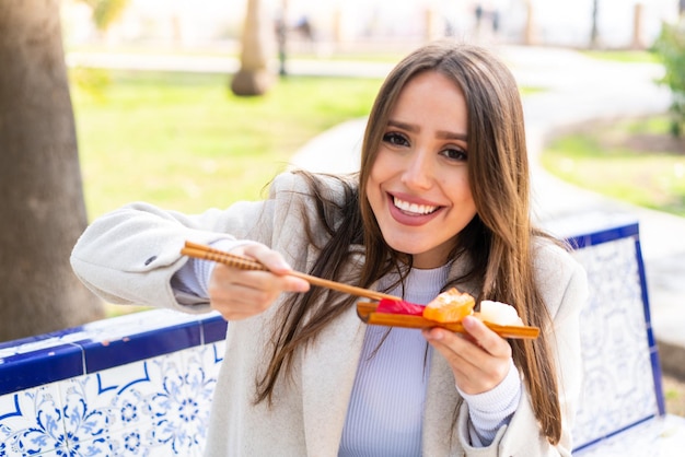 Mujer bonita joven sosteniendo sashimi al aire libre