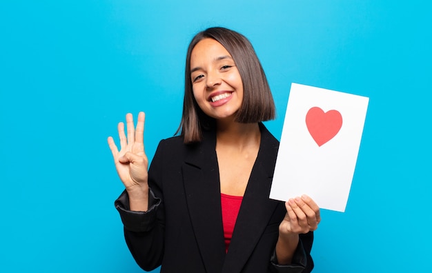 Mujer bonita joven sosteniendo una tarjeta de corazón