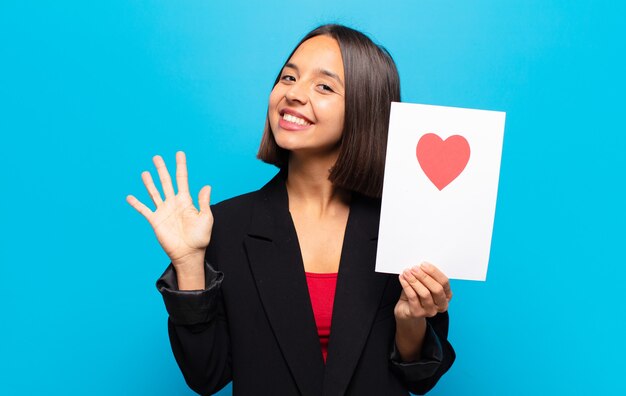 Mujer bonita joven sosteniendo una tarjeta de corazón