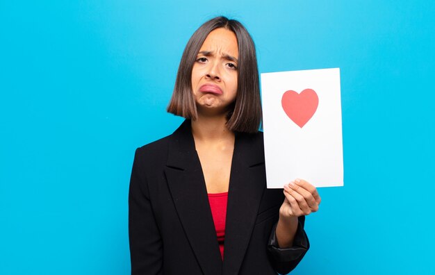 Mujer bonita joven sosteniendo una tarjeta de corazón