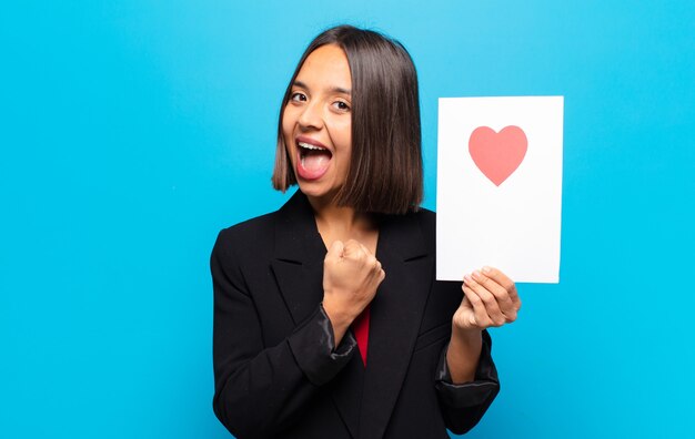 Mujer bonita joven sosteniendo una tarjeta de corazón