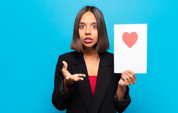 Mujer bonita joven sosteniendo una tarjeta de corazón