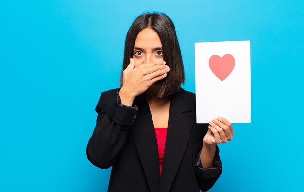 Mujer bonita joven sosteniendo una tarjeta de corazón