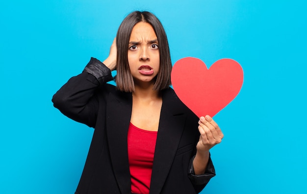 Foto mujer bonita joven sosteniendo una tarjeta de corazón