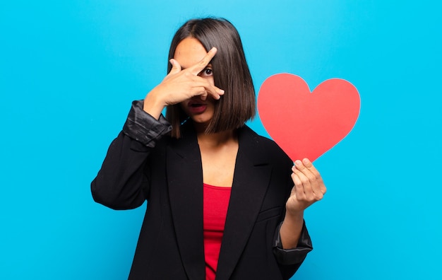 Foto mujer bonita joven sosteniendo una tarjeta de corazón