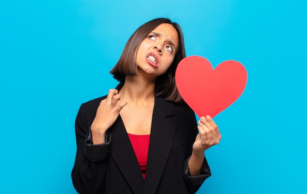 Mujer bonita joven sosteniendo una tarjeta de corazón