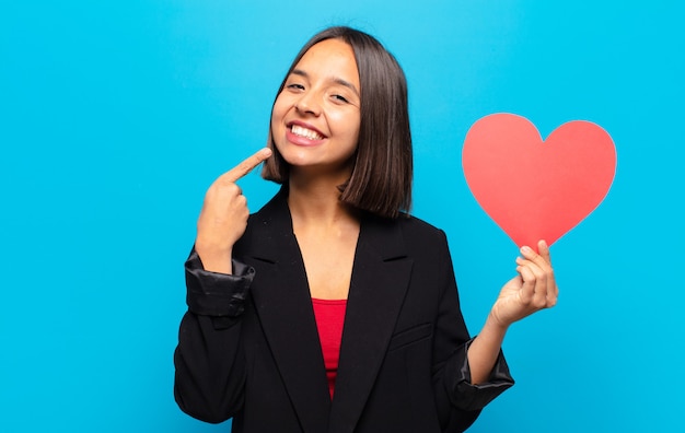 Mujer bonita joven sosteniendo una tarjeta de corazón