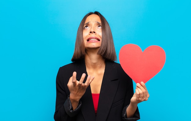 Mujer bonita joven sosteniendo una tarjeta de corazón