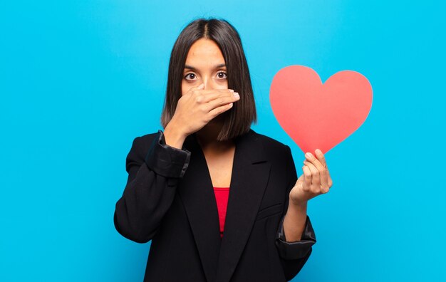 Mujer bonita joven sosteniendo una tarjeta de corazón